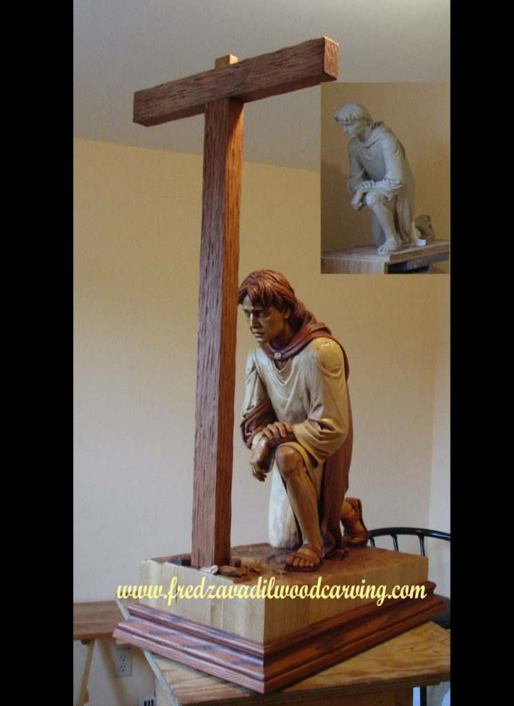 Sculpture of a man kneeling in front of a cross. Religious woodcarving by Fred Zavadil